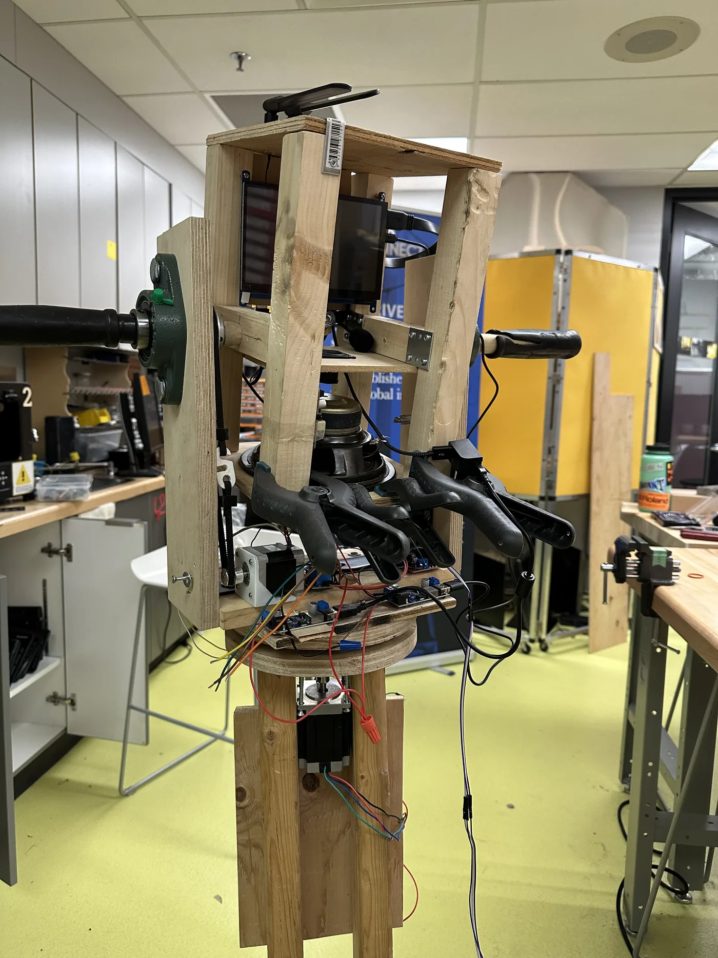 Wooden test rig on a shop stand carrying the screen, both handles, the belt drive, slip ring, and stepper motor with wiring exposed