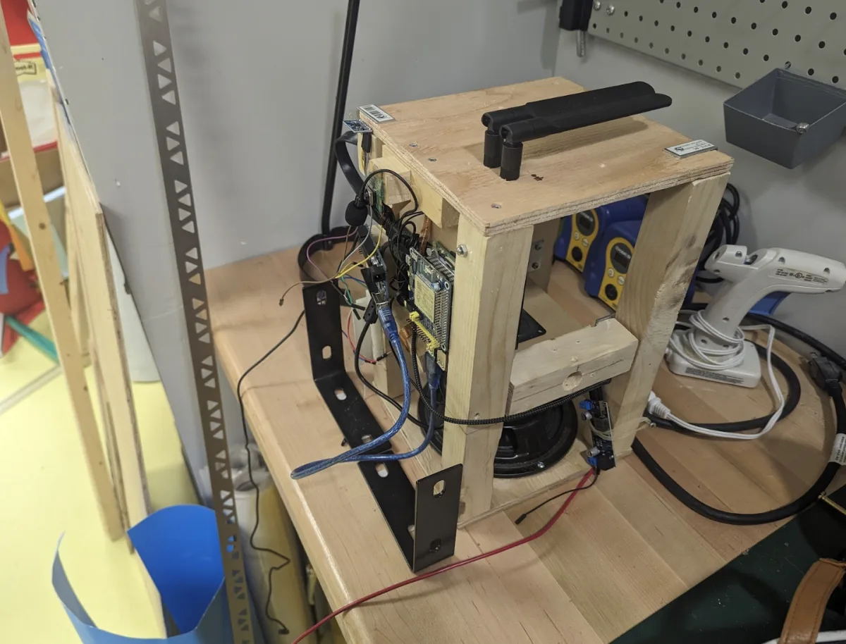 Plywood test rig on a workbench holding a Raspberry Pi, LTE antenna, motor, and loose wiring